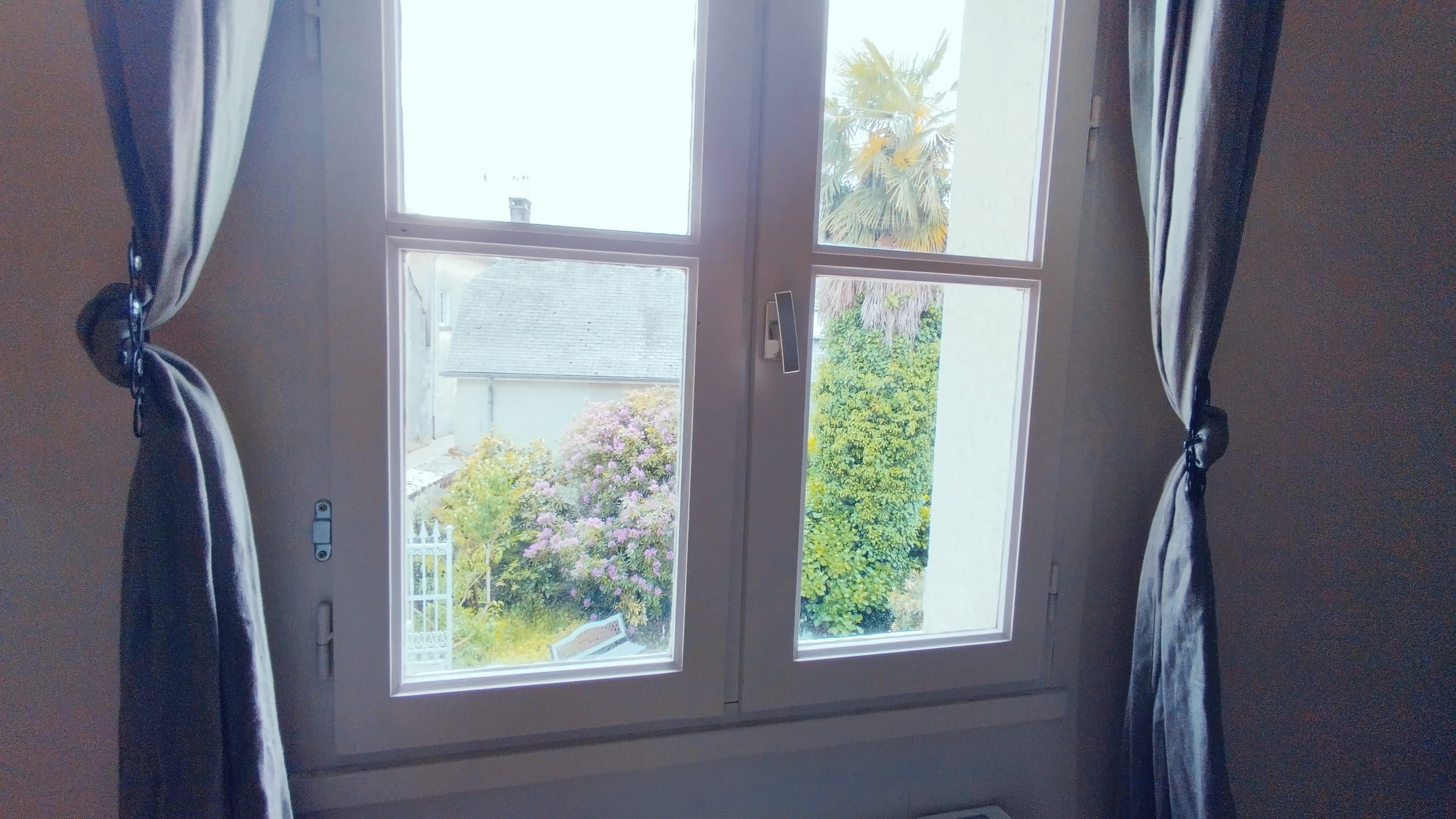 Chambre avec bureau ancien et fenêtre ouverte sur le jardin