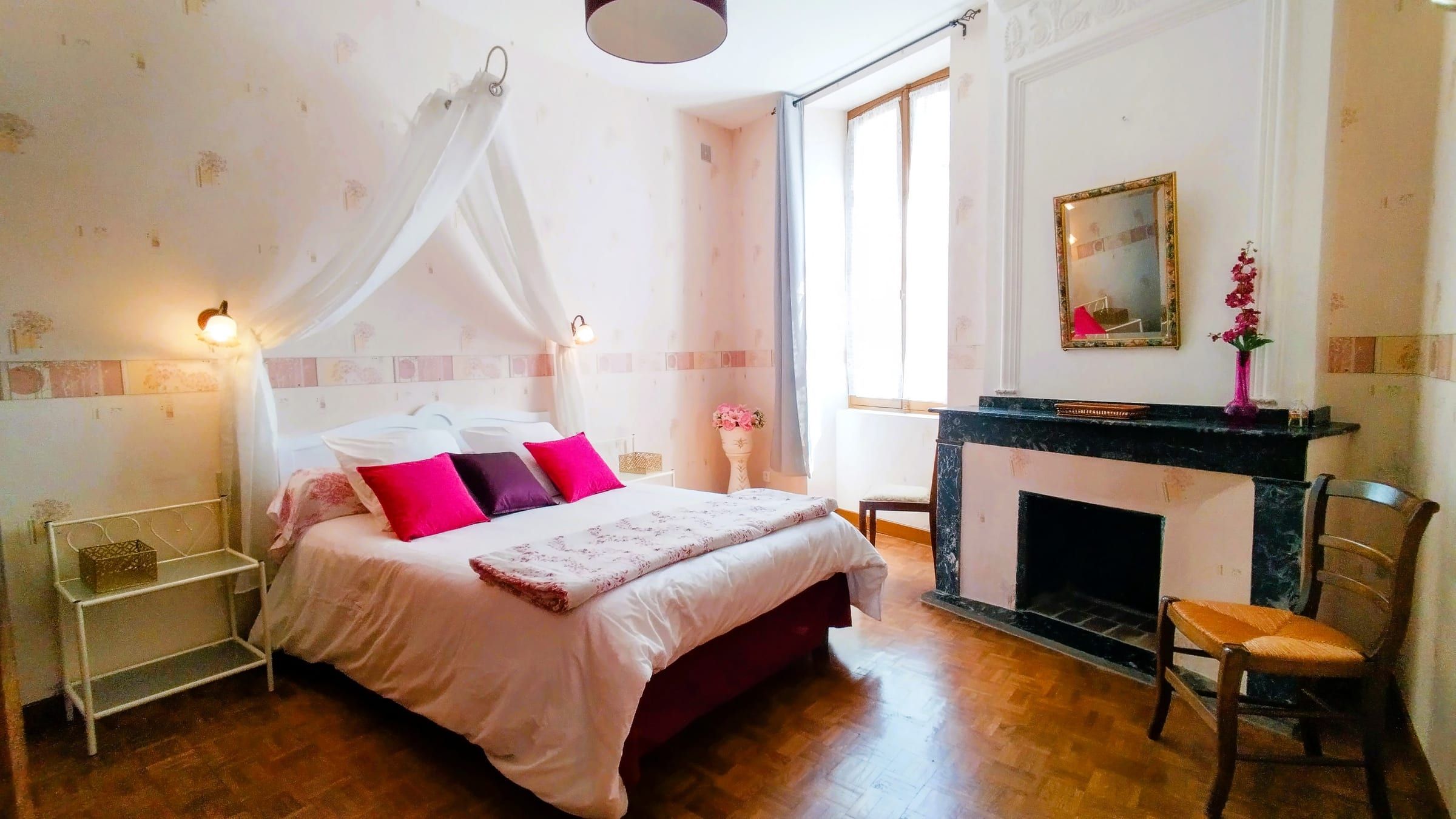 Chambre romantique au rez-de-chaussée avec lit double, ciel de lit et cheminée en marbre