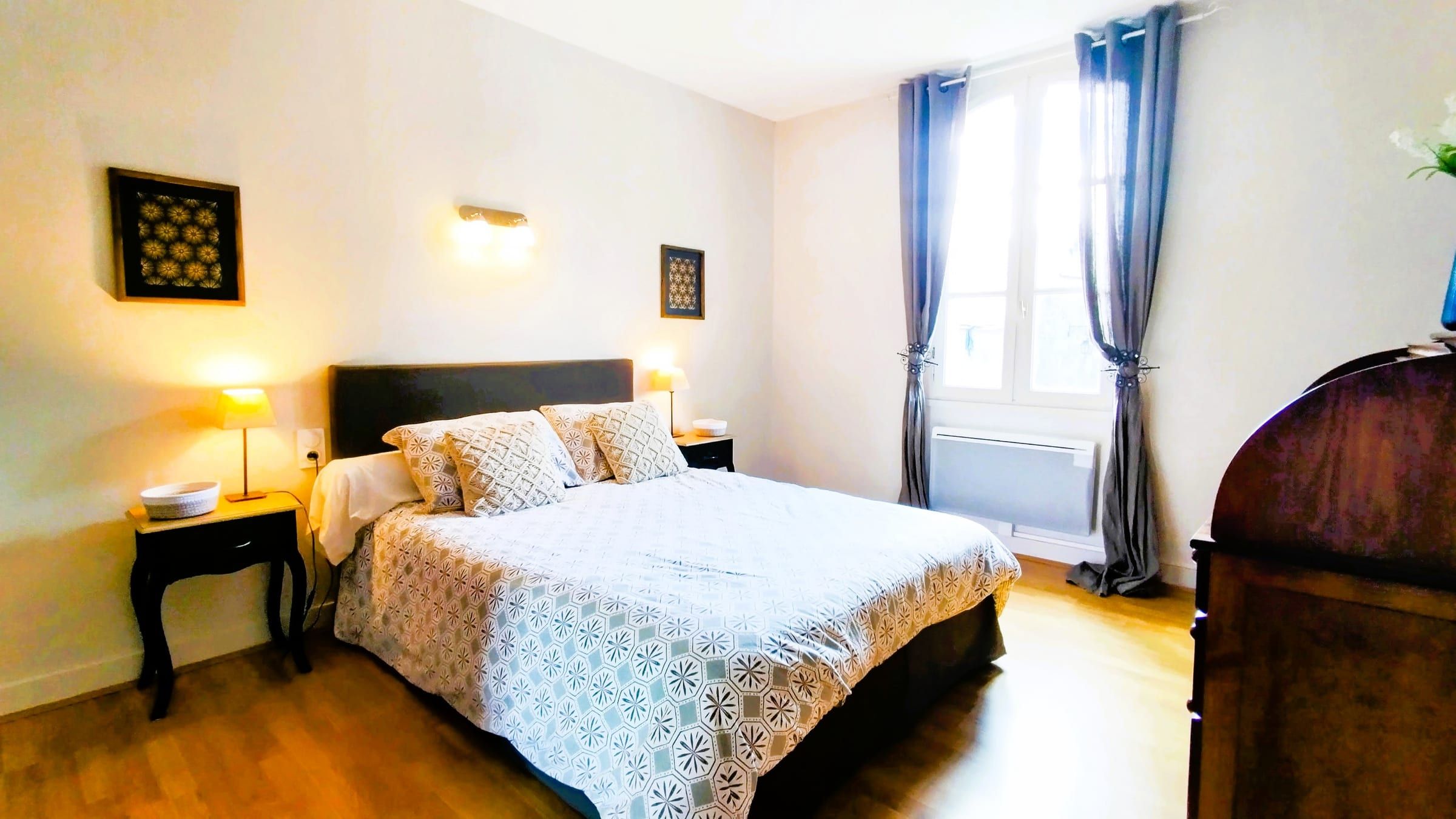 Chambre lumineuse avec lit double, linge blanc et grandes fenêtres