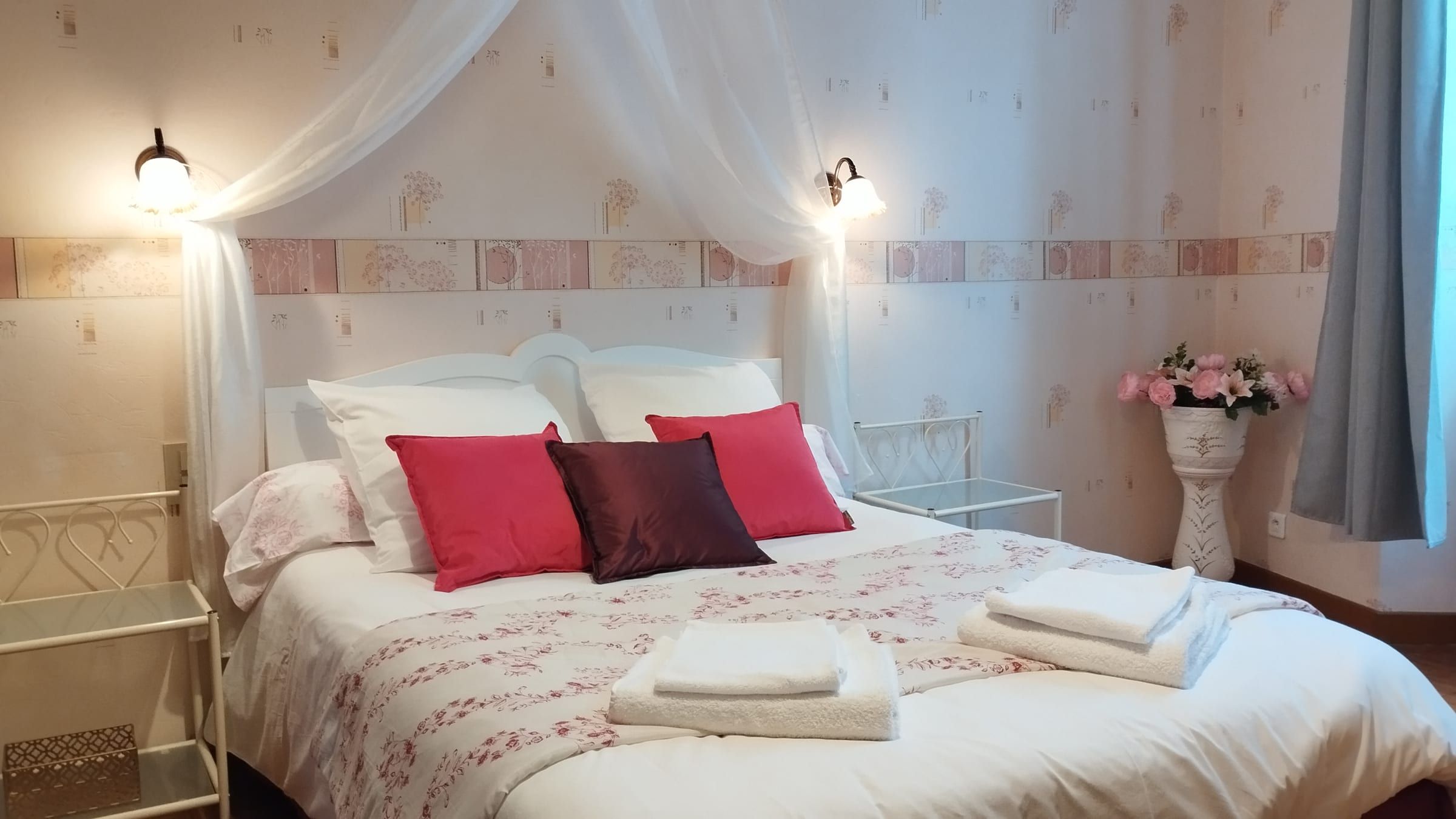 Chambre romantique avec coussins rouges et ciel de lit