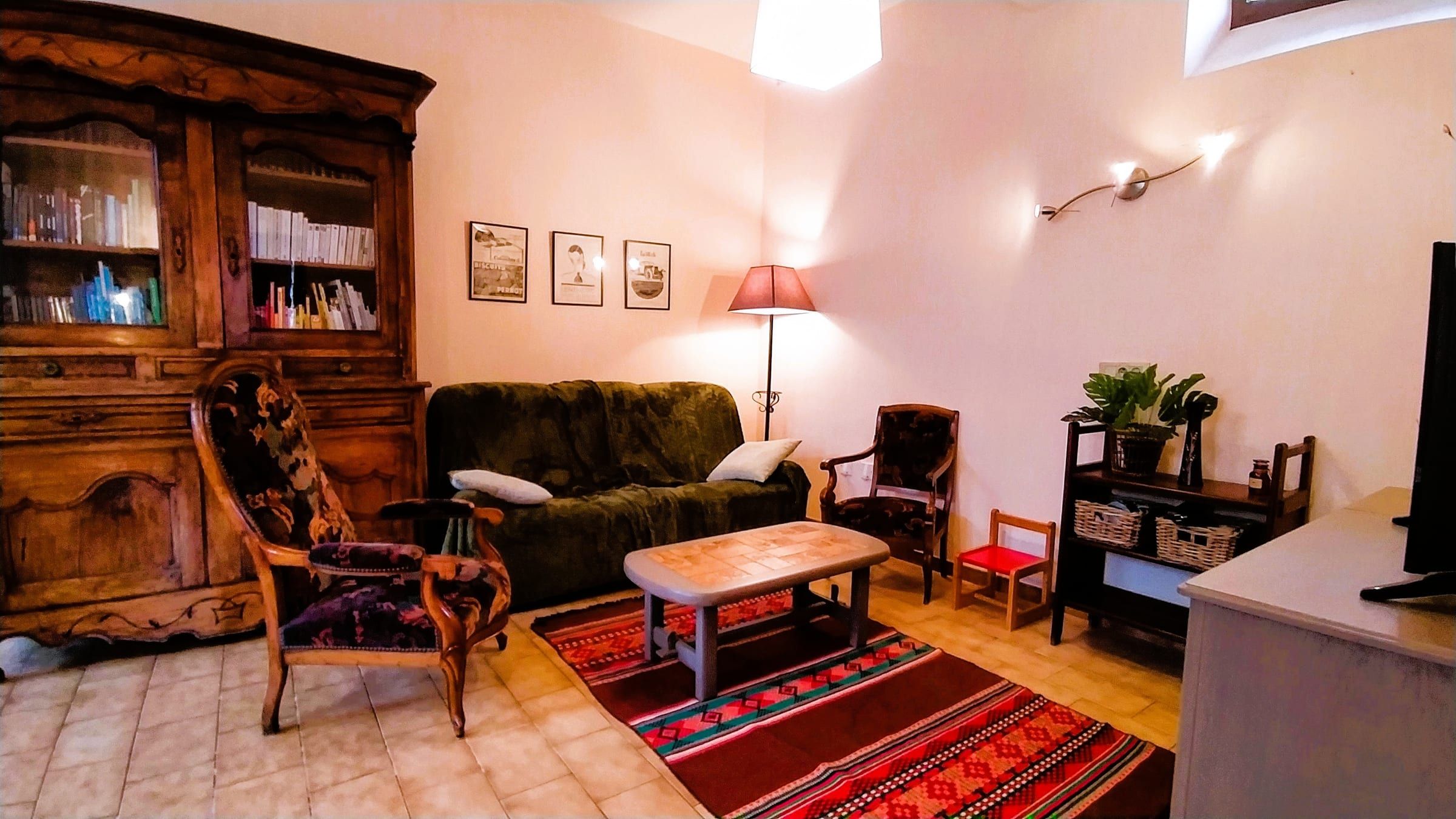 Salon chaleureux avec canapé, fauteuils anciens, bibliothèque et tapis rouge
